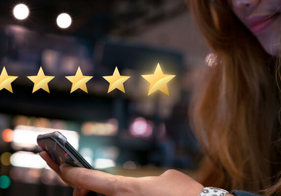 Millennial woman submitting star rating feedback on mobile device after internet shopping experience Millennial woman submitting star rating feedback on mobile device after internet shopping experience